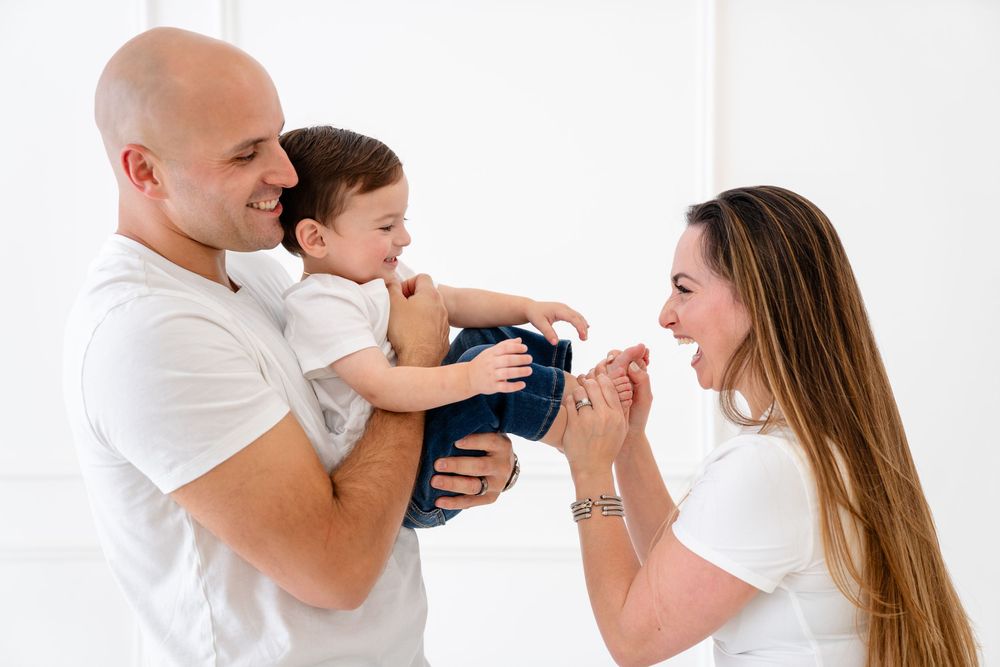 Playful family moments captured in white studio showing joyful interactions against light background.