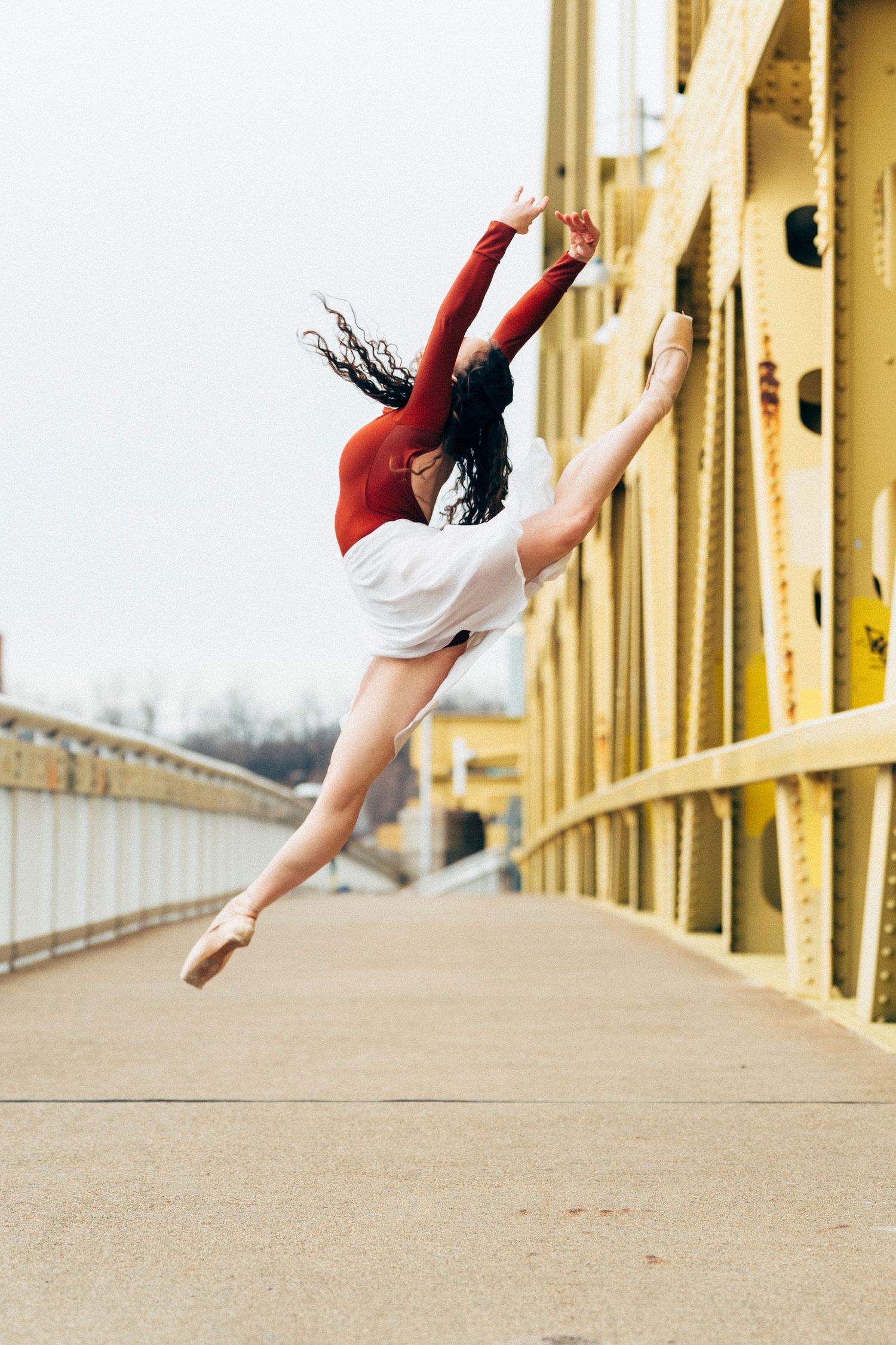 Ballet dancer extending her leg in a dramatic pose near Fort Duquesne at Point State Park during sunset pittsburgh dance photography