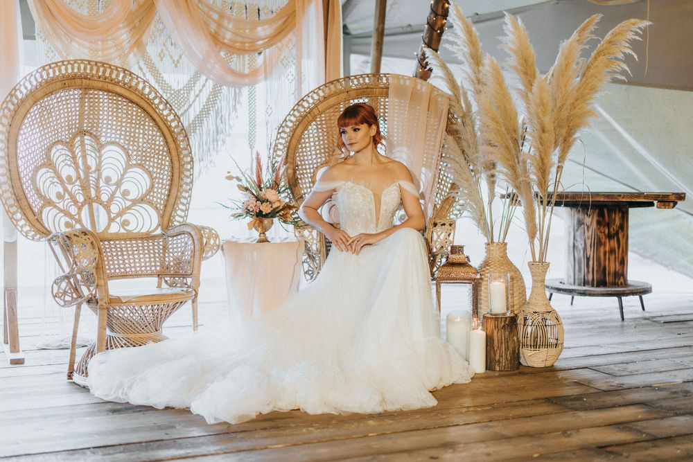 Elegant peacock chair arrangements with white tulle and floral decorations create a dreamy bohemian wedding setting at Nuddock Wood Lake.