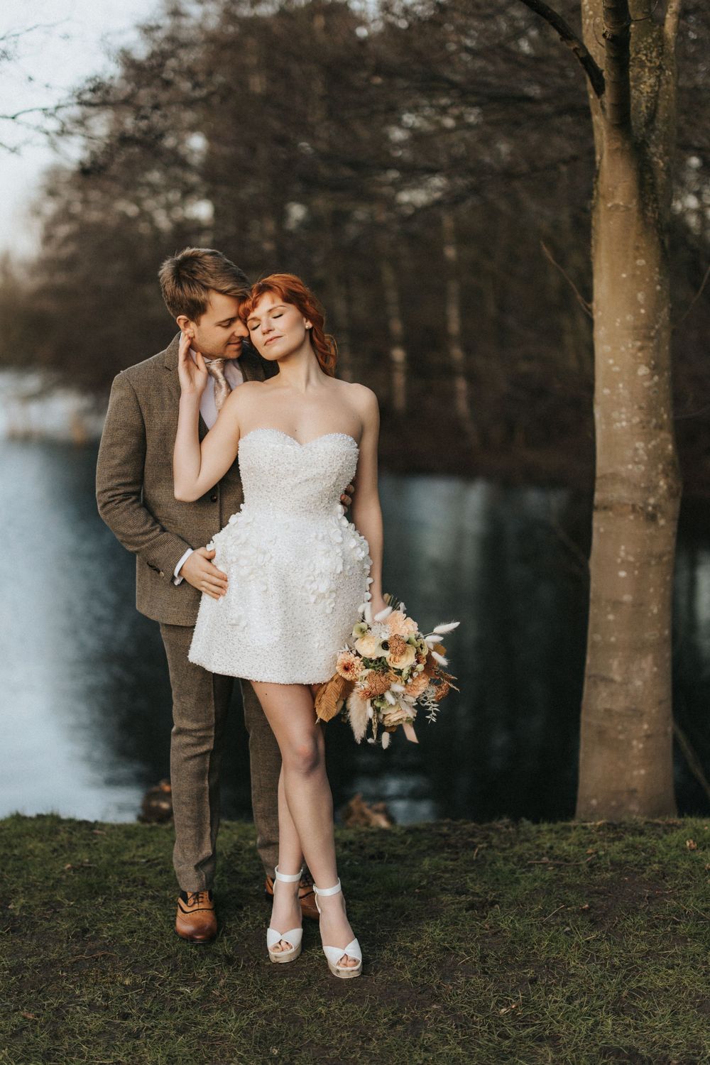 Romantic couple shares intimate moment by lakeside in autumn at Nuddock Wood Lake.