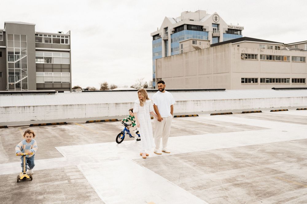 Skateboarder performs trick sequence on rooftop parking deck in urban setting during sunset.