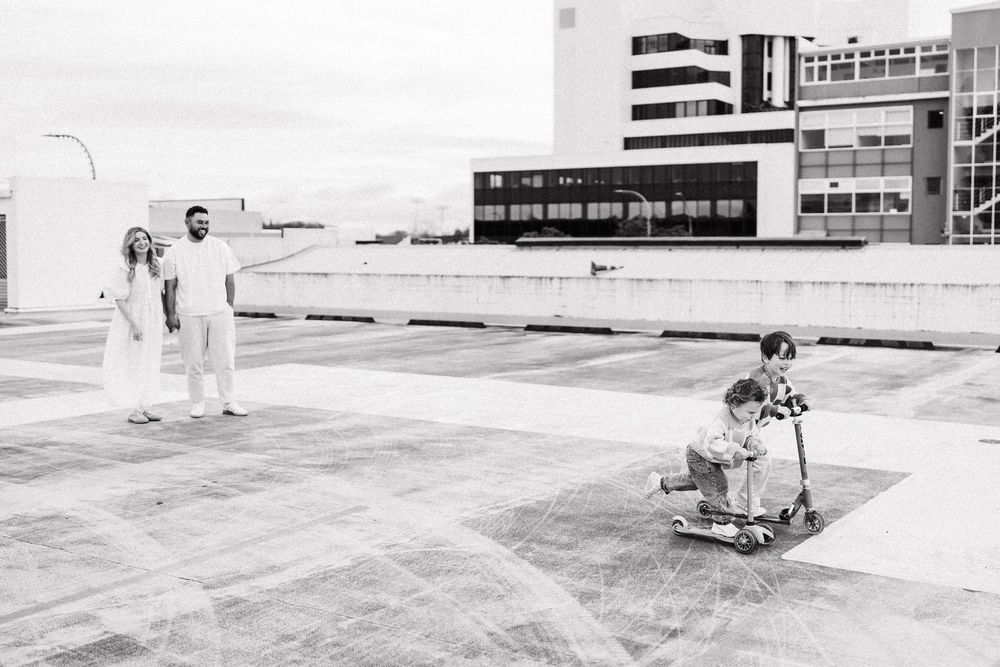 Black and white panoramic sequence shows construction workers surveying progress on a large commercial building site.