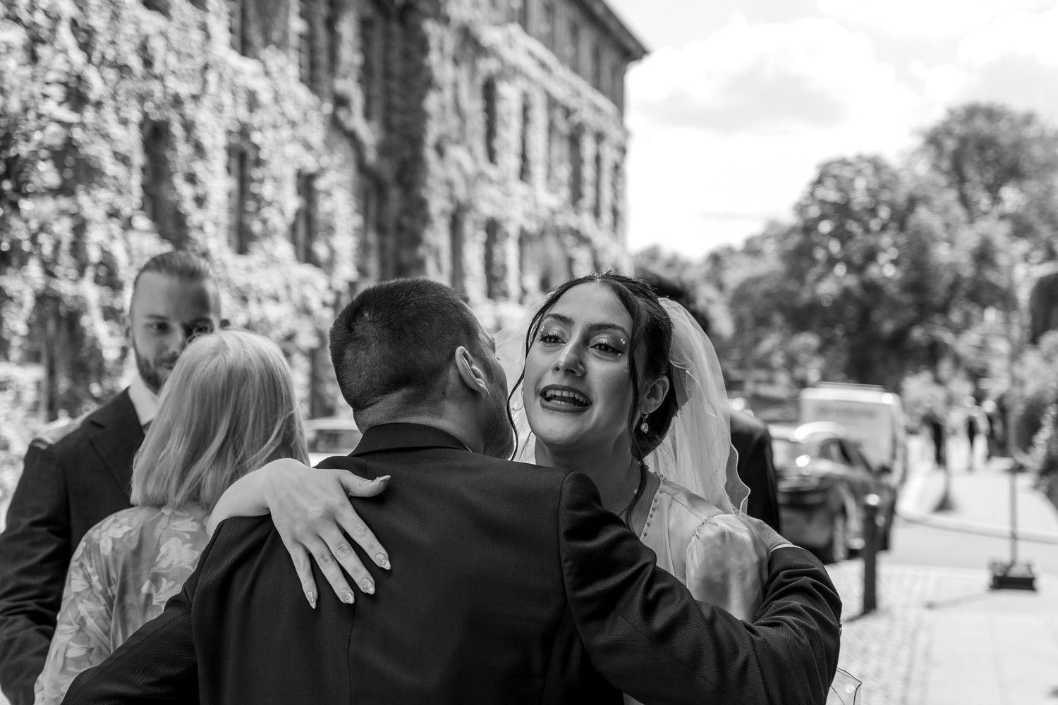 Hochzeitsfotograf Standesamt Spandau Berlin – Brautpaar Umarmung mit Gast vor Altbaufassade Schwarz-Weiß