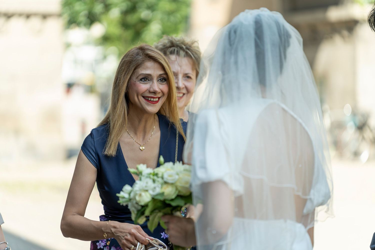 Hochzeitsfotograf Standesamt Spandau Berlin – Braut begrüßt Gast mit Blumenstrauß draußen