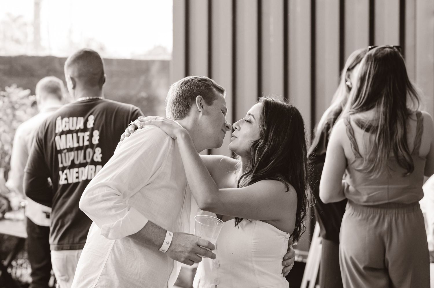 Black and white candid photo showing romantic moment between a couple dancing at a casual event.