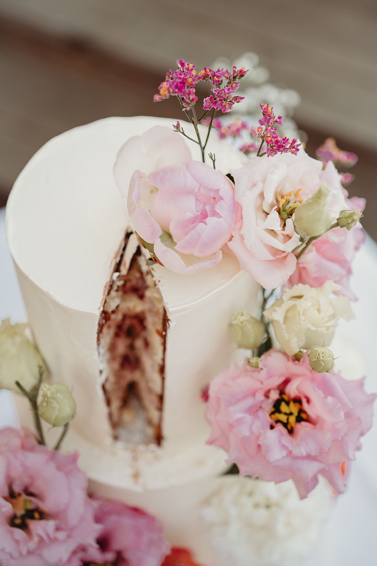 Bröllopstårta i tre våningar dekorerad med färska blommor. Tårtan går i pasteliga toner av rosa och gräddvit. Inspiration för bröllopstårtan