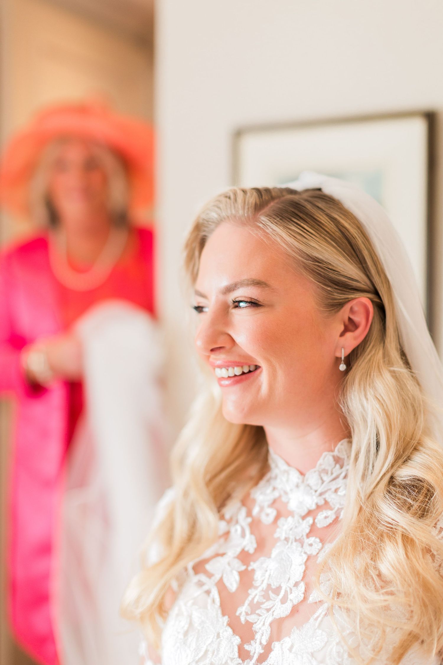 Bride in white lace dress smiling and looking to the side with her mum behind her at Ellenborough Park Cotswolds - Hayley Elizabeth photo