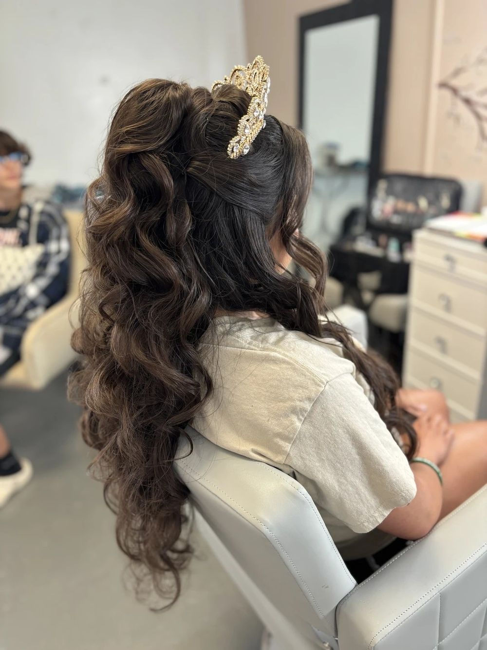 Long dark wavy hair styled in an elegant half-up style with a decorative gold hair clip at a salon.