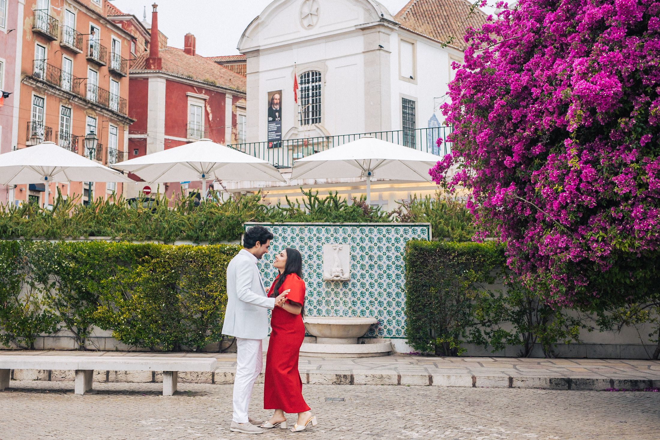 Engaged Indian couple embracing near iconic Lisbon architecture.