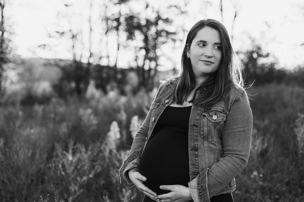 Candid portrait session in a natural outdoor setting with long grass and moody lighting.