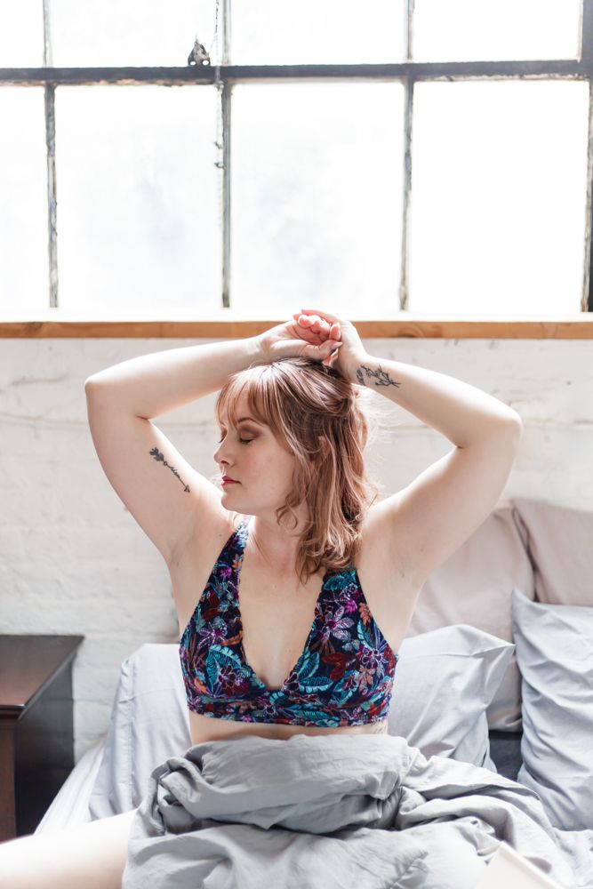 Artistic boudoir portrait with natural window lighting and minimalist white decor.