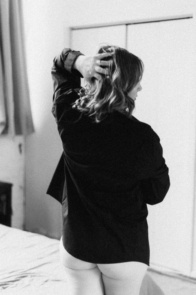 Black and white photo showing the back view of someone in a dark jacket with tousled hair.