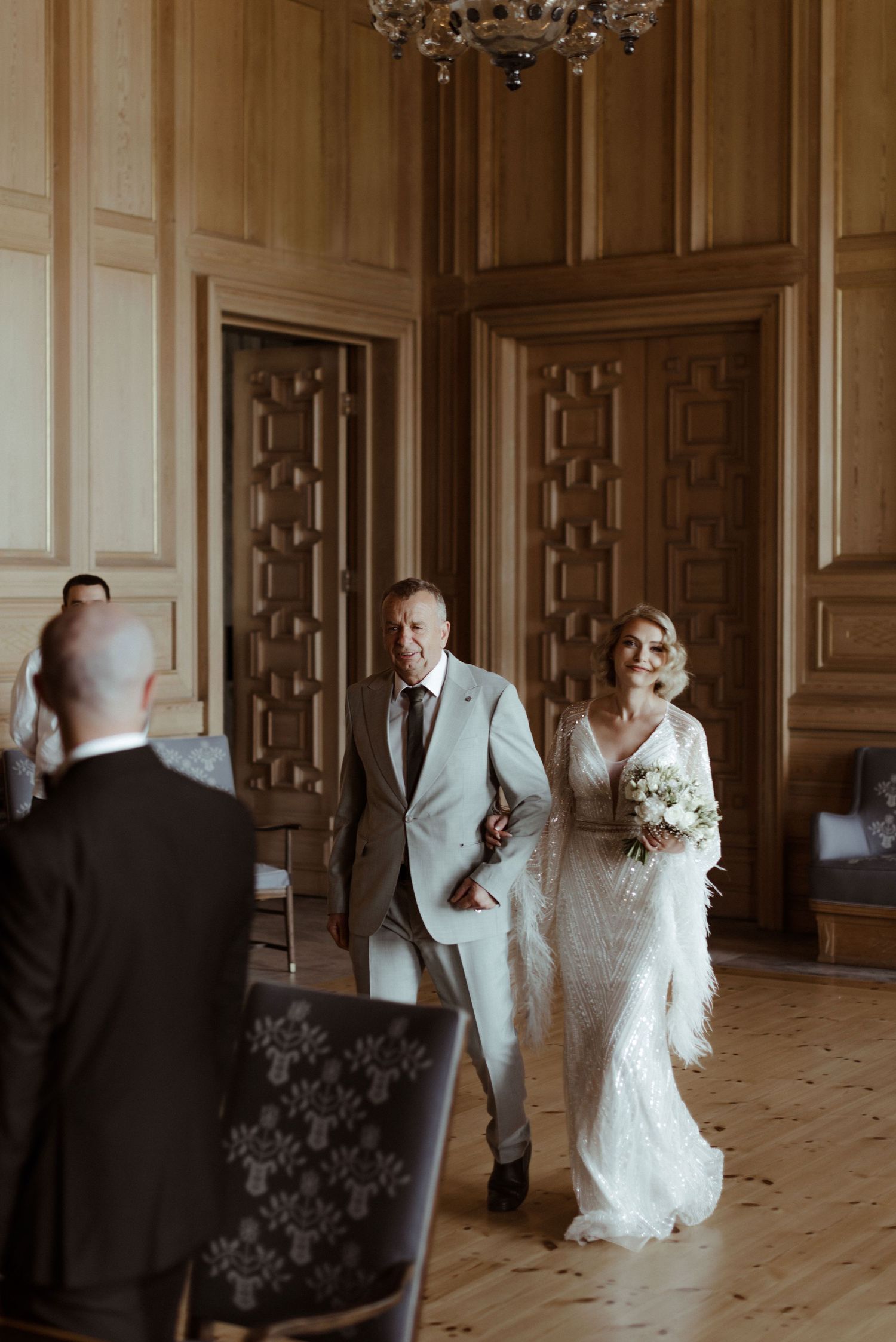 A romantic wedding sequence showing the couple walking through an elegant wood-paneled hallway with an ornate chandelier.