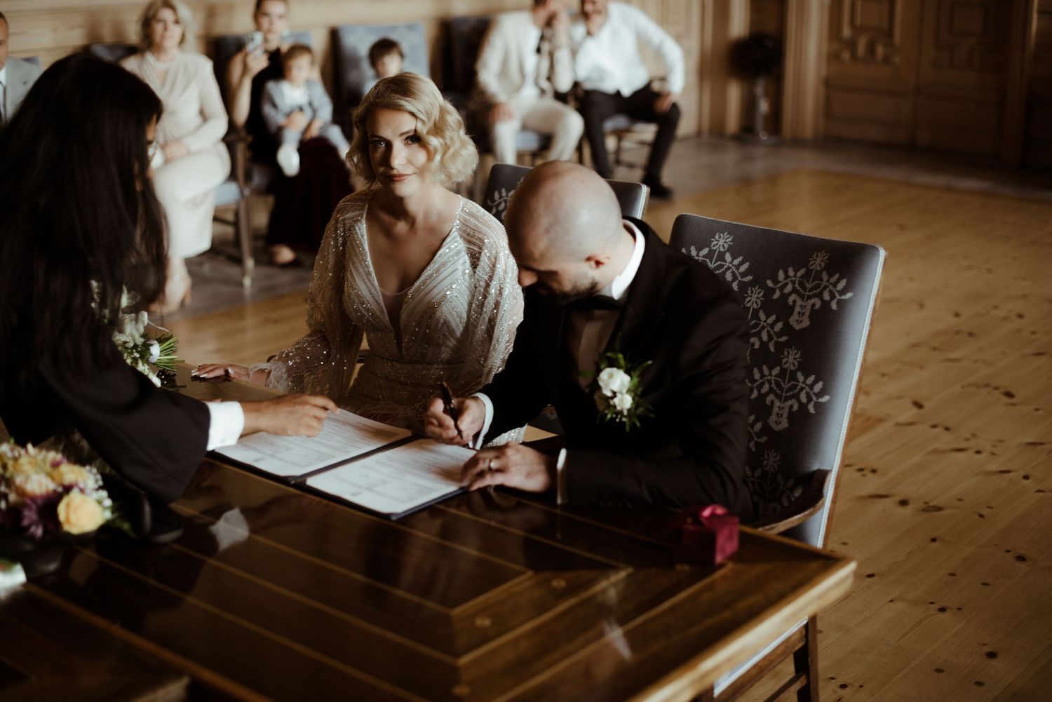 Wedding guests sign the guestbook and share well wishes at an elegant wooden table during the reception.