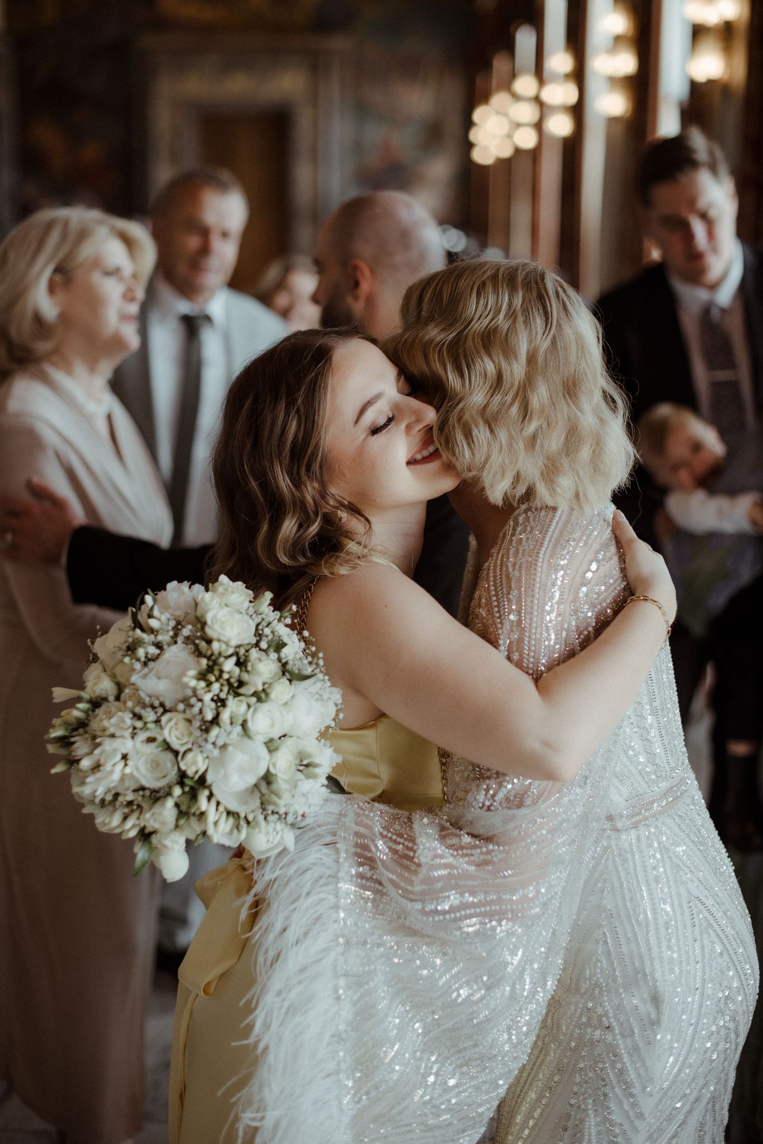 Two brides in sparkly white wedding dresses share an intimate kiss on their special day.