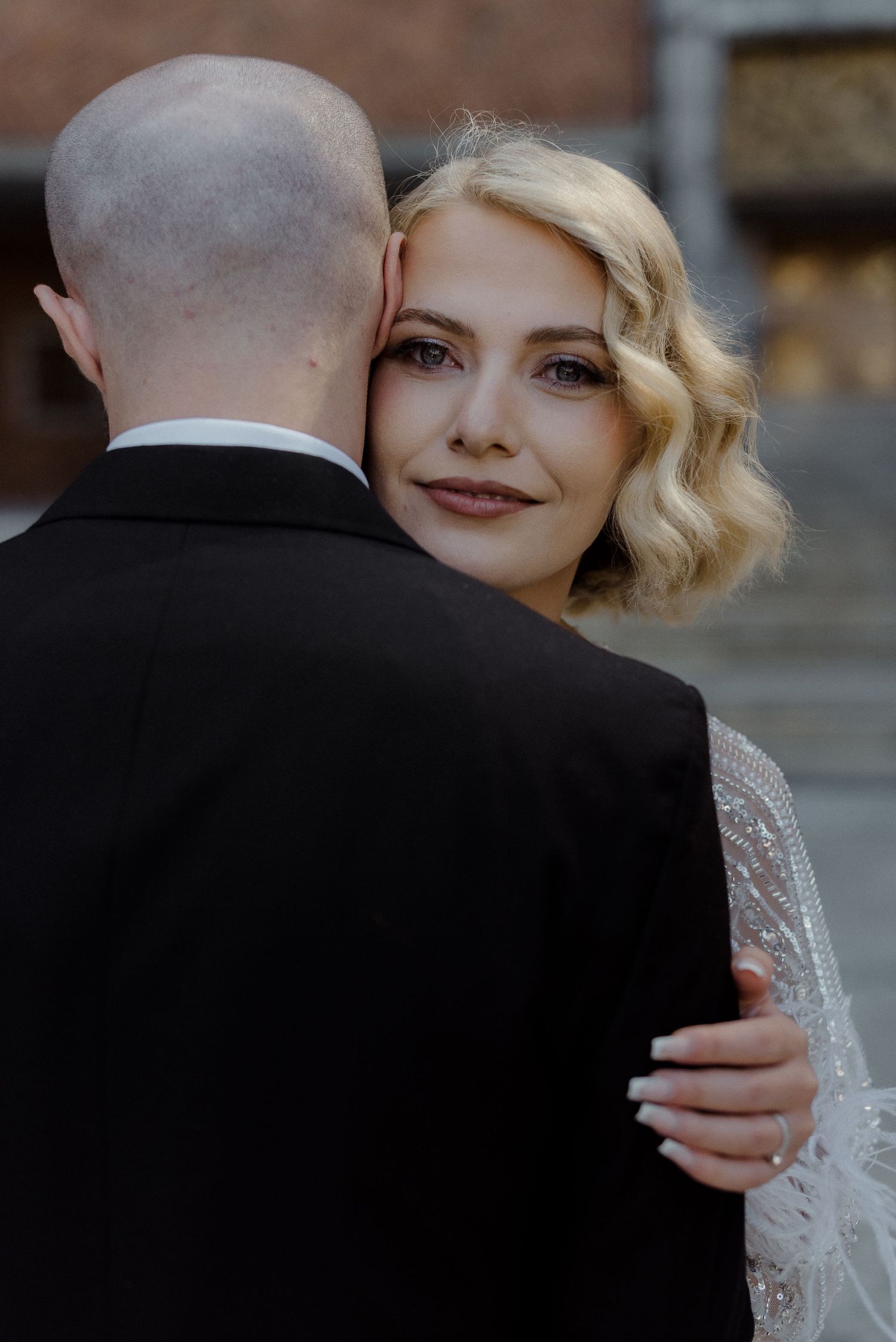 A couple embraces during their wedding photoshoot with vintage-inspired styling and elegant attire.