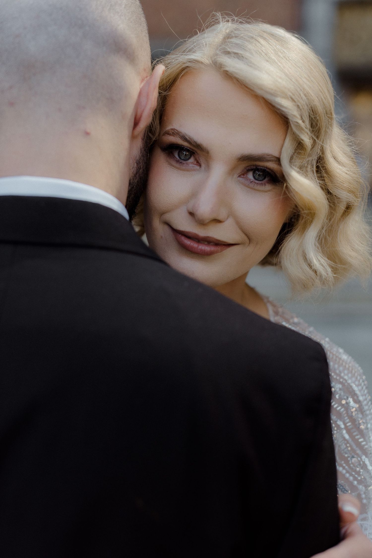 Close up wedding portrait of a bride with blonde wavy hair and red lipstick in a romantic pose.