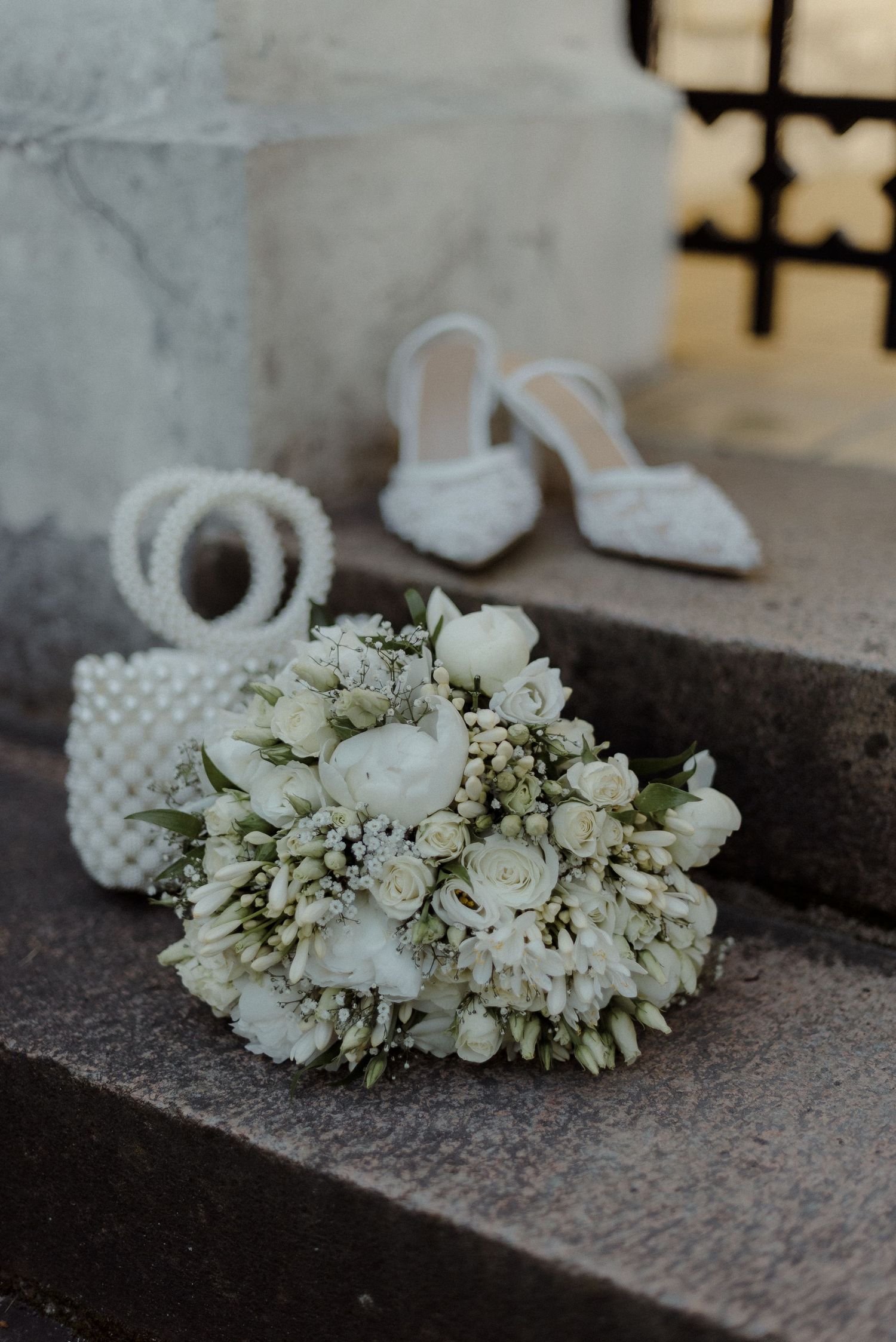 White floral hair accessory and wedding details displayed on concrete surface.