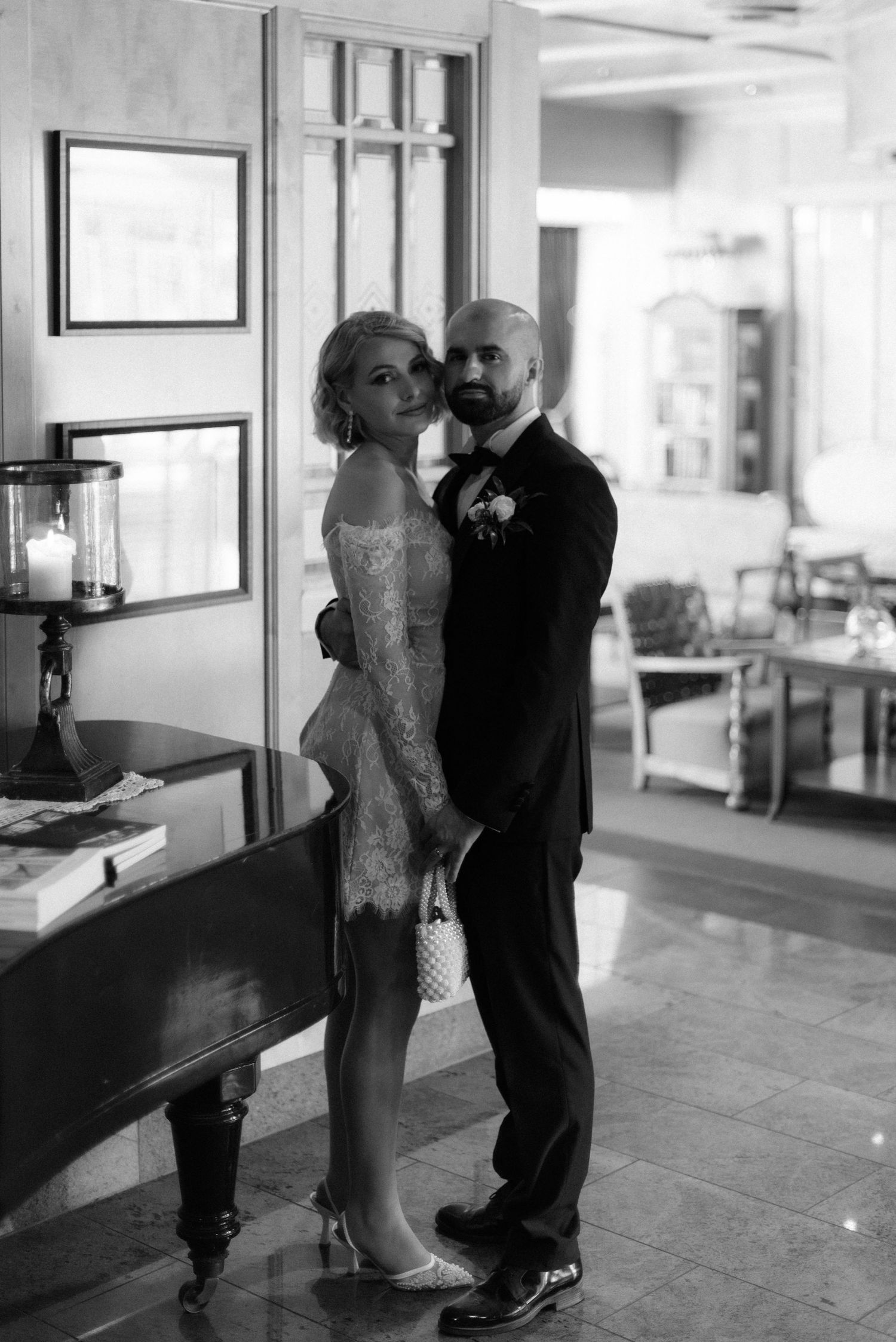 A couple shares an intimate moment in black and white photography during their wedding celebration at an elegant indoor venue.