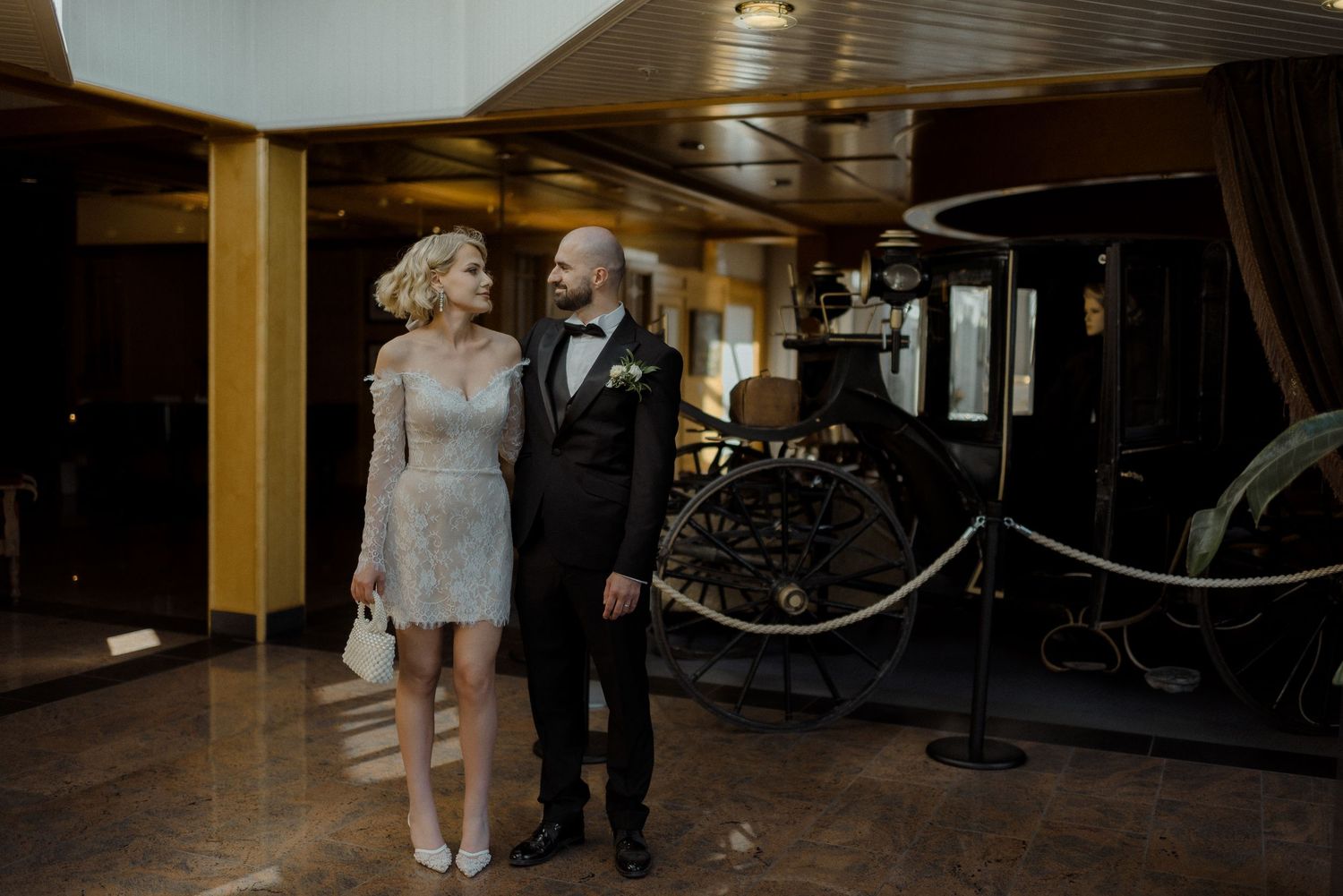 A sequence of people walking through an elegant wood-paneled hallway in formal attire during an event.