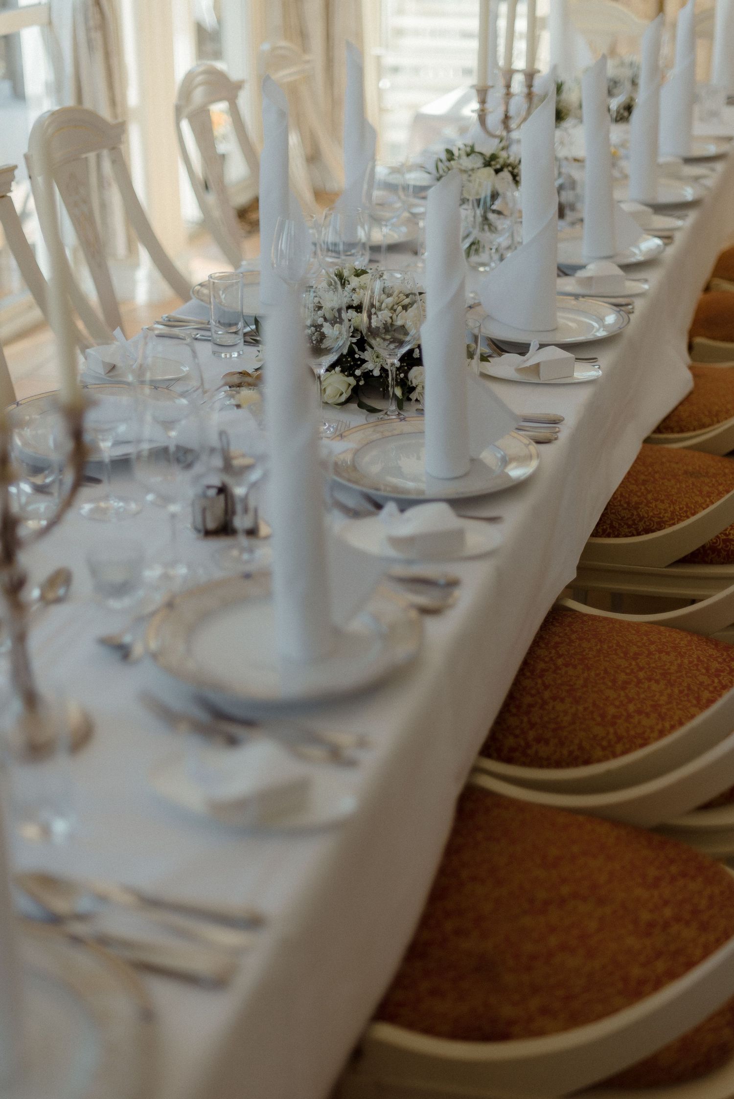 White banquet chairs and elegant table settings arranged for a formal dining event.