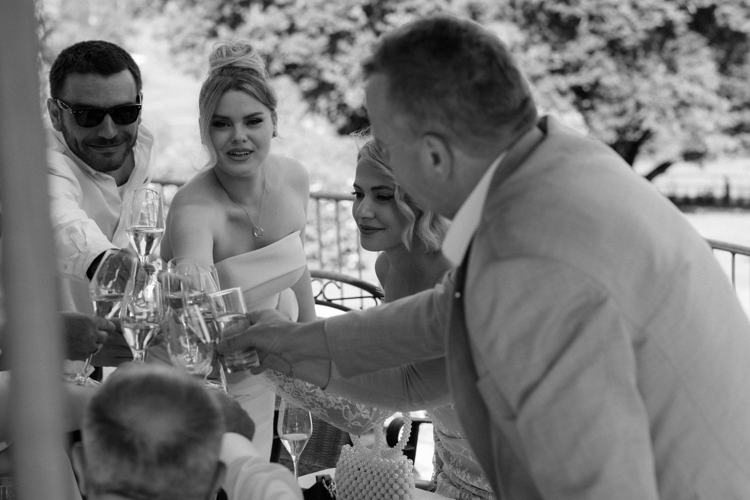 Black and white candid photos of guests enjoying an outdoor wedding reception at dining tables and benches.