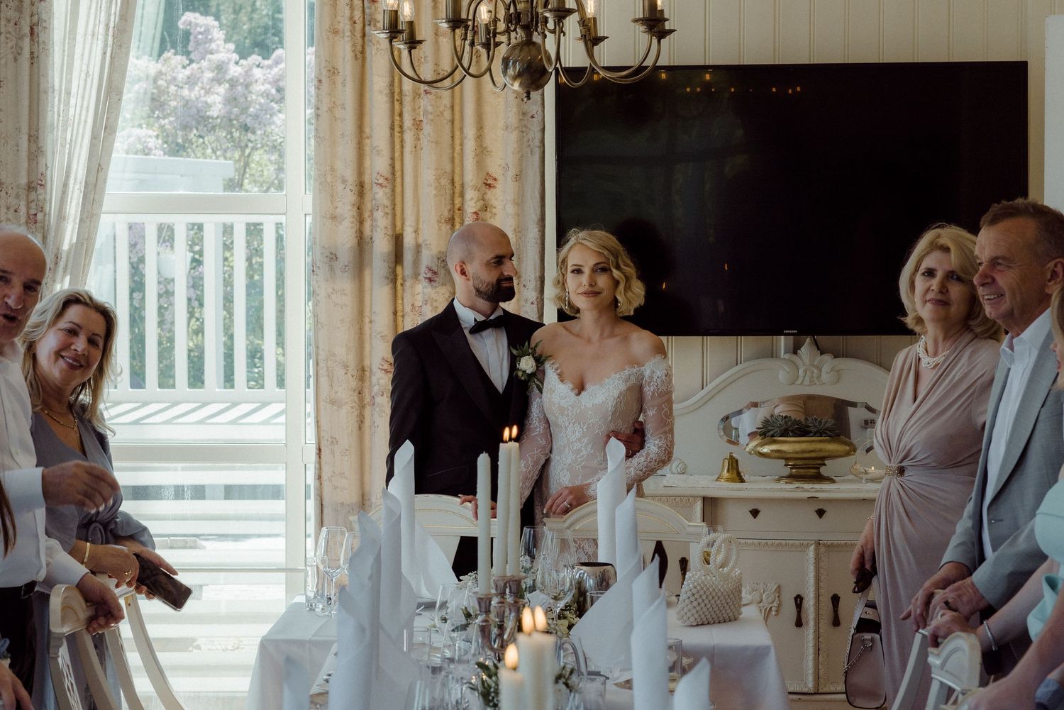 Wedding party gathered around a dining table with candlelight during a celebration at an elegant indoor venue.