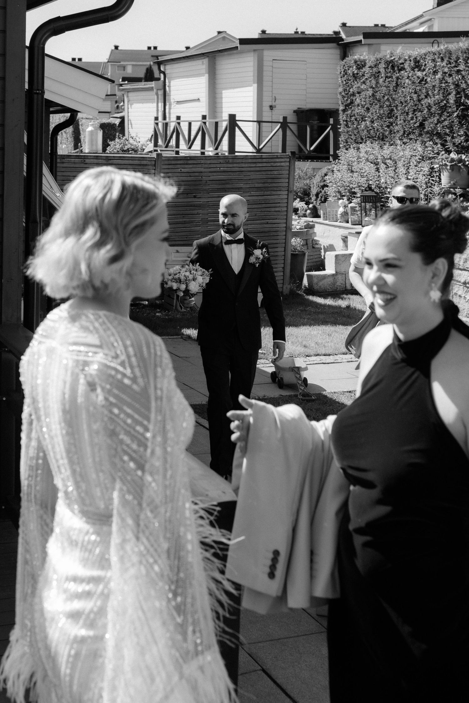 Group of figures in dark and light contrasting outfits walking and interacting outdoors in black and white.