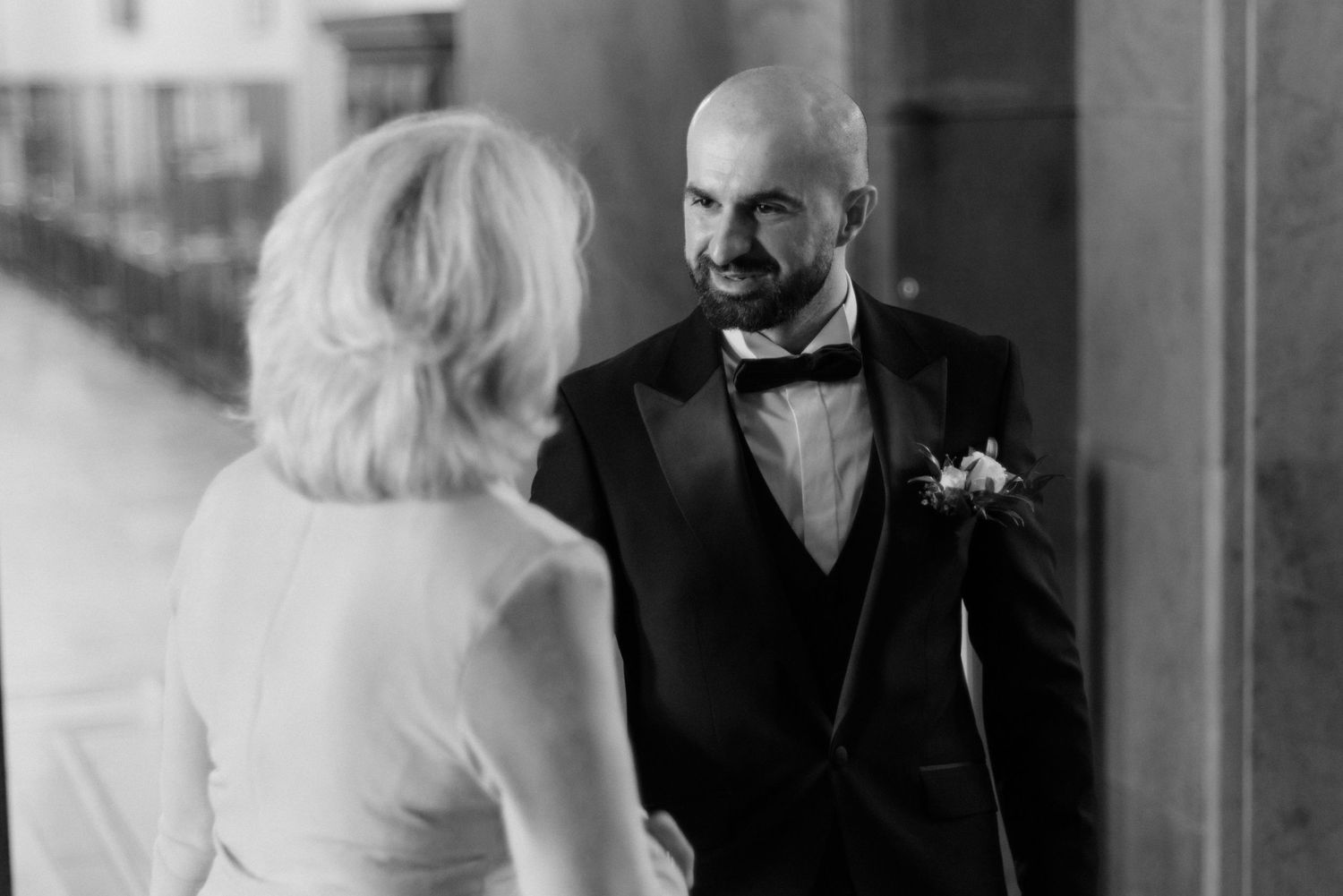 A candid black and white wedding photo showing a heartfelt moment between a couple in formal attire at their ceremony.