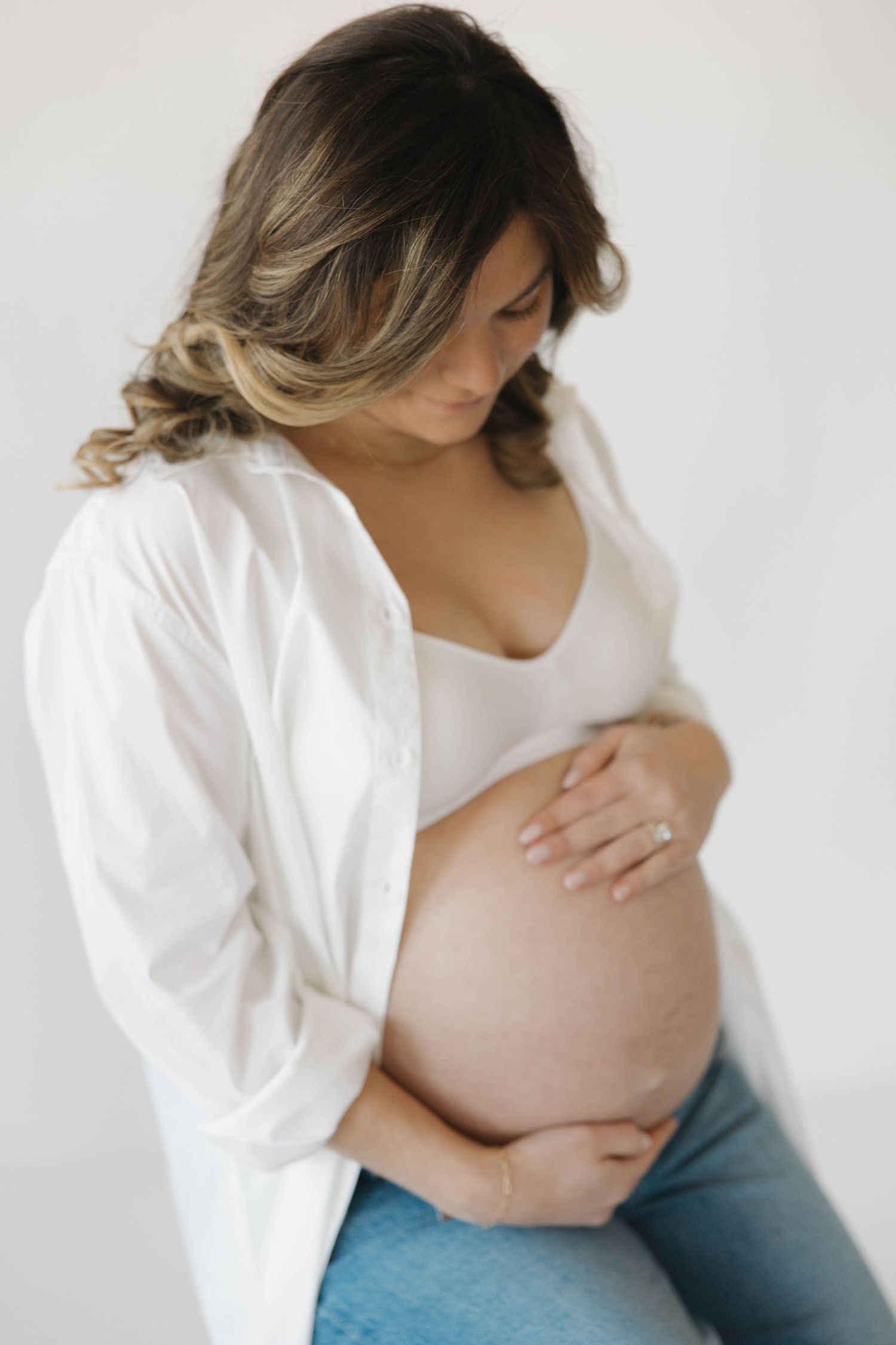 Series of minimalist maternity photos showing a pregnant belly in a white shirt against light background.