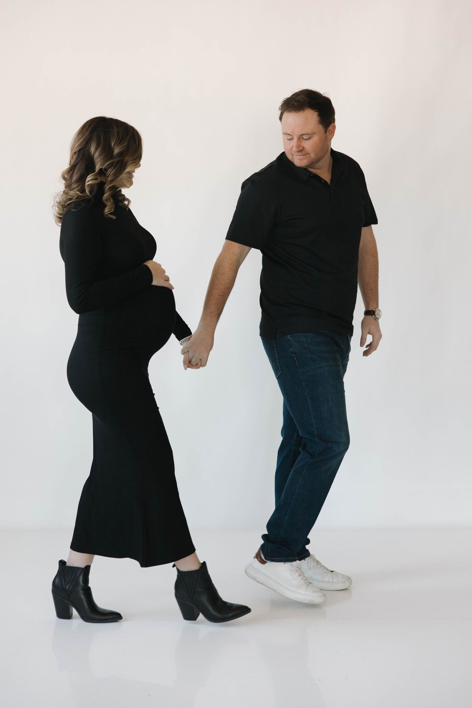 Dance sequence showing two people in black attire performing dynamic movements against white backdrop.