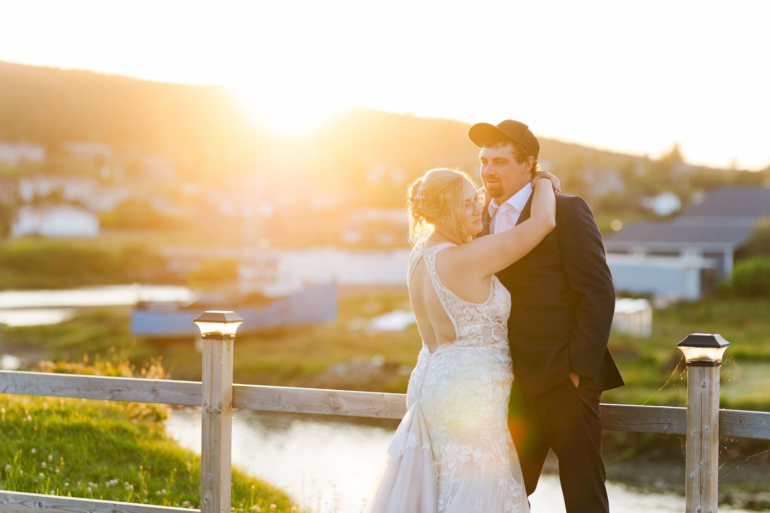 A romantic sunset wedding photo features a couple embracing on a scenic bridge with golden light illuminating the scene.