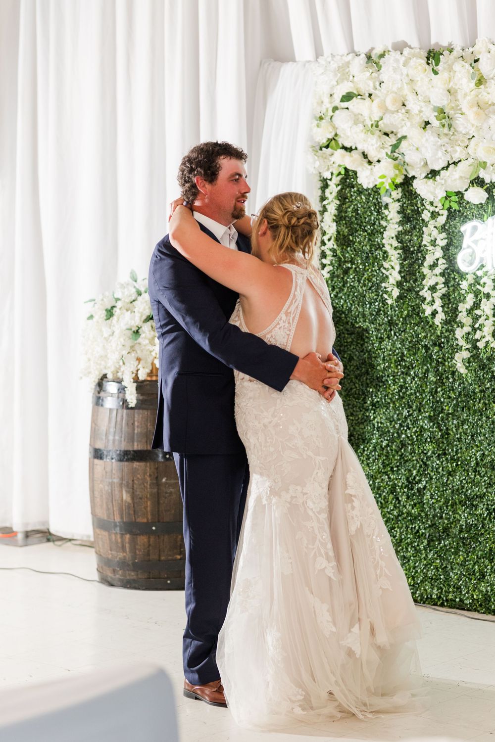A couple shares a romantic moment on the dance floor at their elegant wedding reception decorated with white flowers.