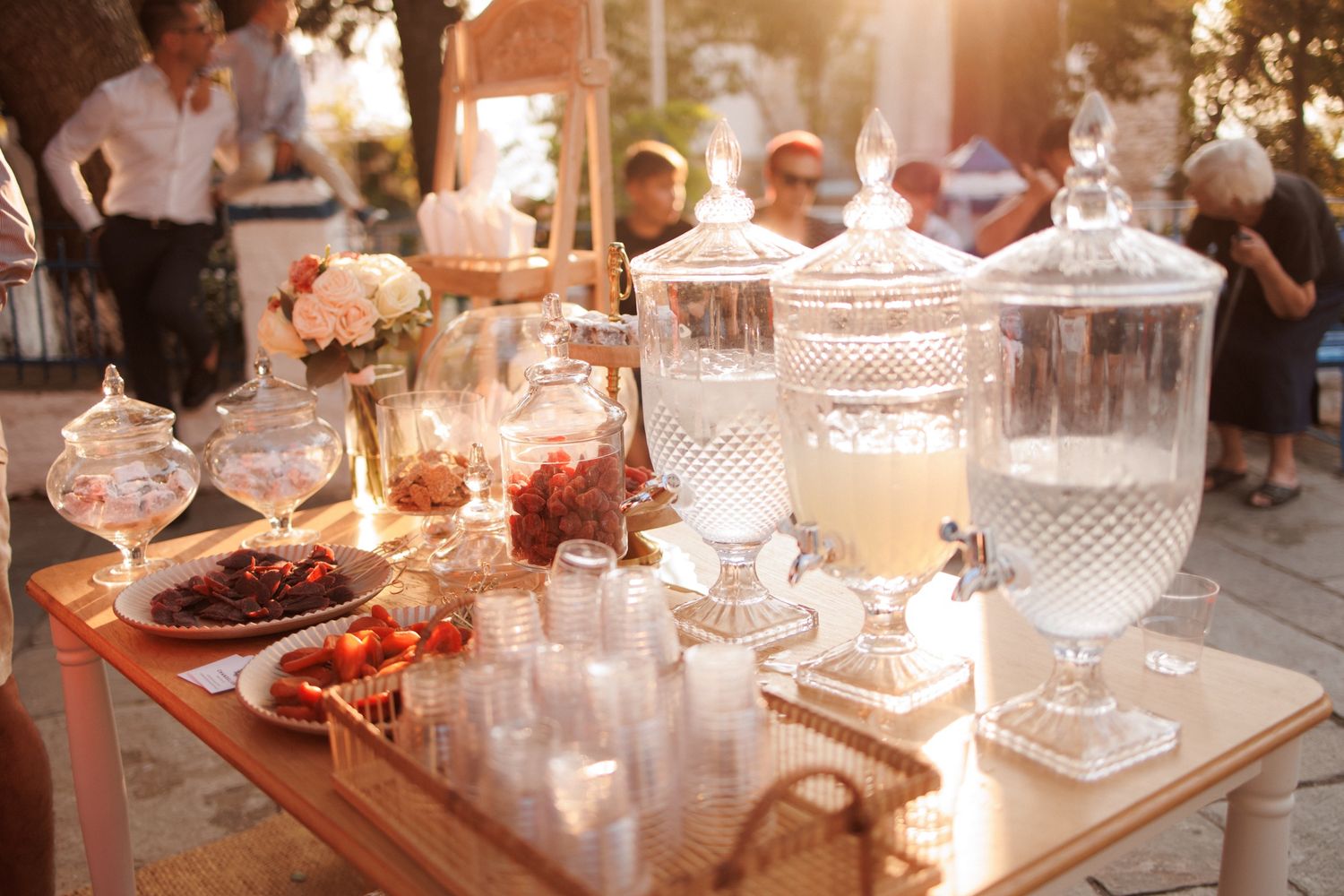 An elegant dessert table at a party features crystal cake stands, pastries, and candles in a romantic evening setting.