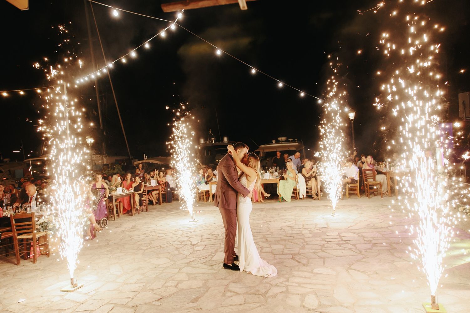 A sequence of eight photos showing sparkling wedding firework fountains lighting up a dark outdoor venue along a pathway.