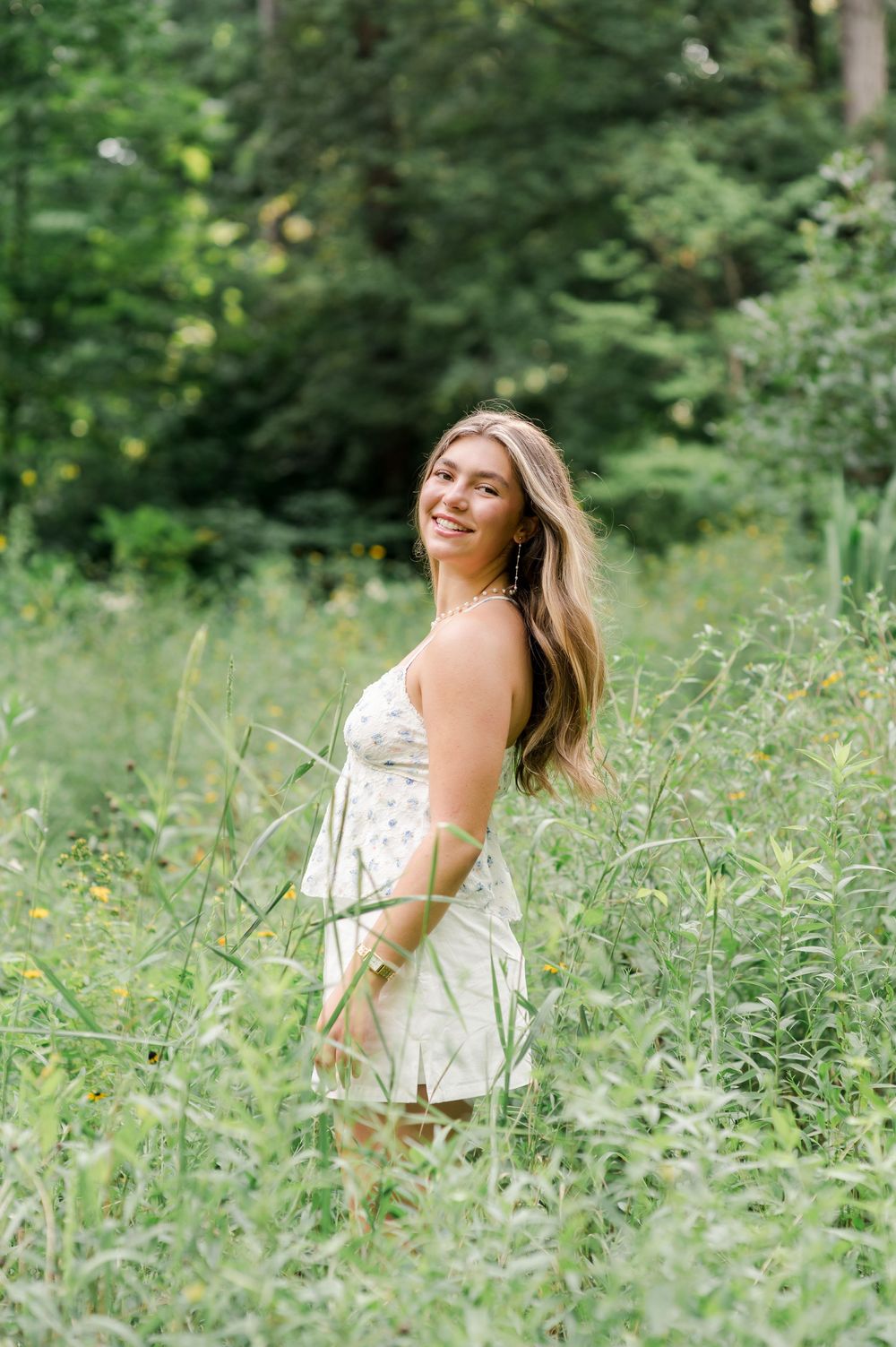 Person in white sundress joyfully spins through a lush green meadow filled with wildflowers on a sunny summer day.