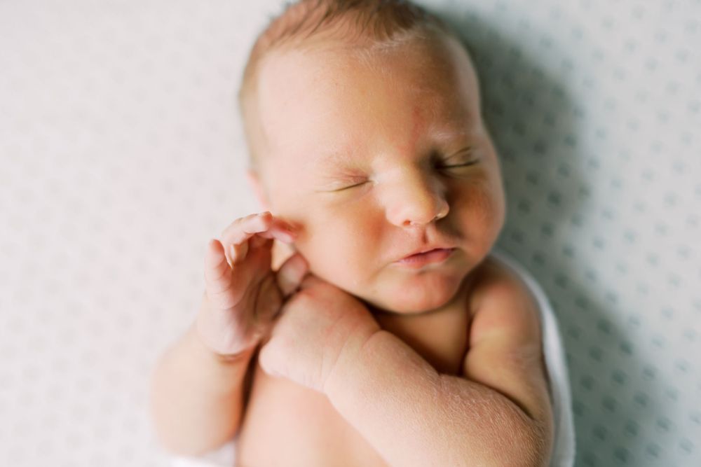 Peaceful sleeping newborn baby with delicate features resting on white background.