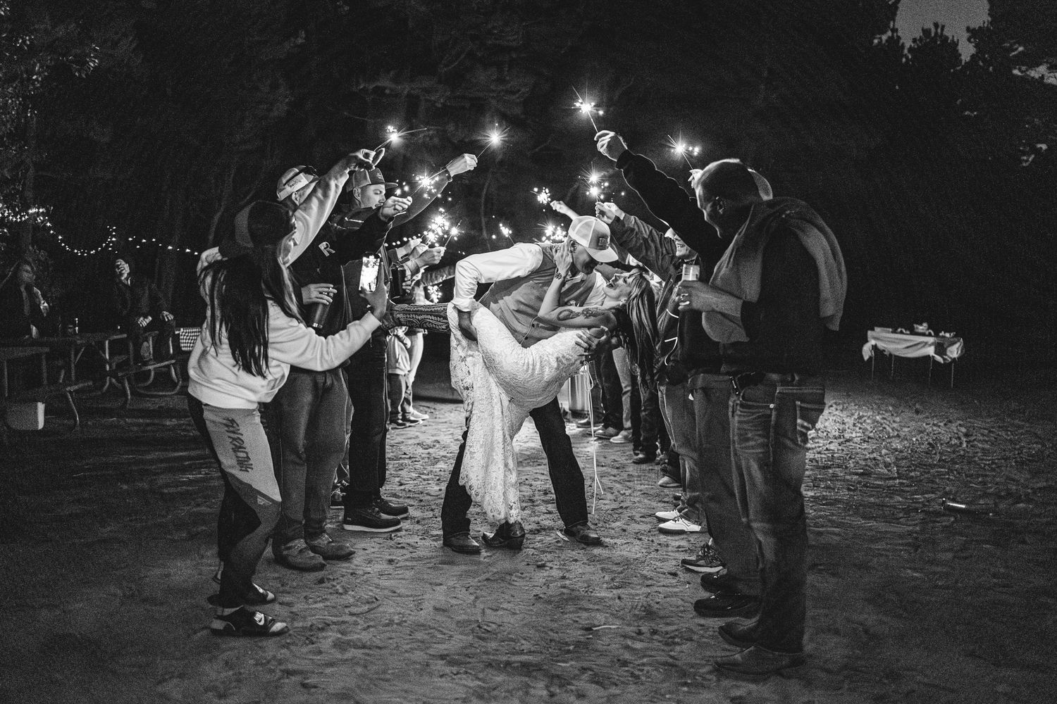Wedding guests form a sparkler tunnel at night for a celebratory moment.