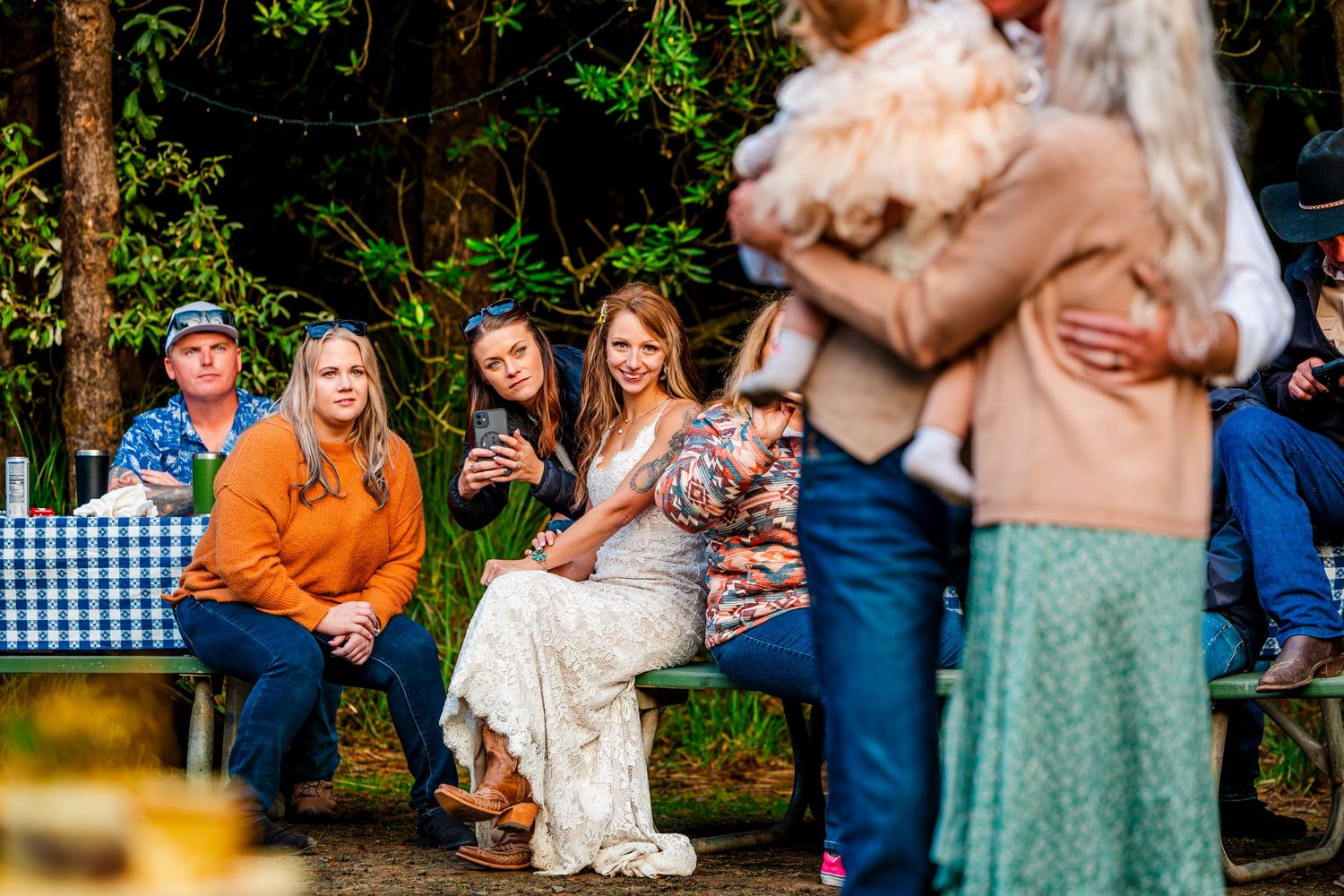 People gathered outdoors at a casual event enjoying drinks and conversation in a natural setting.