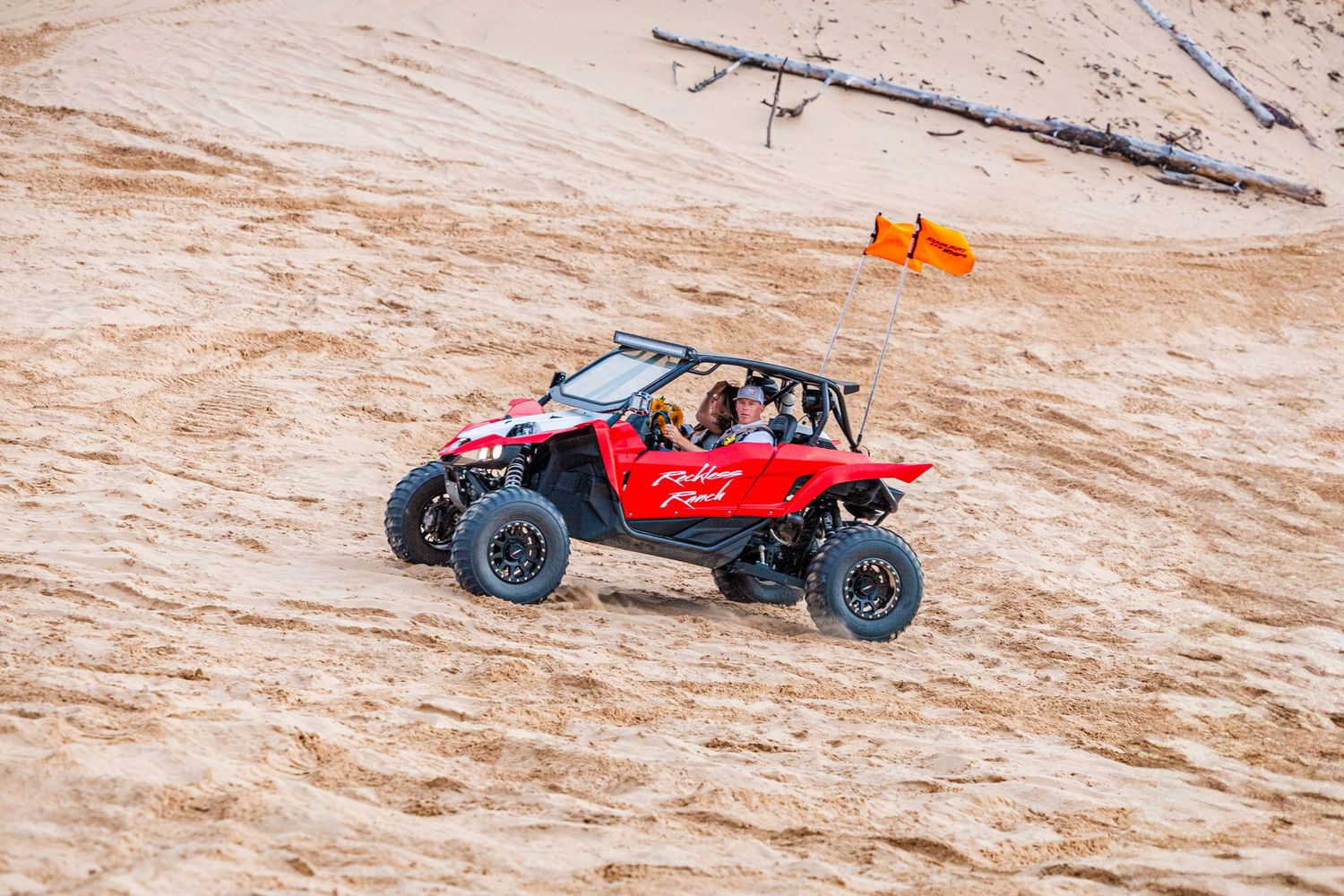 Red off-road buggy racing across sandy desert terrain with scattered brush.