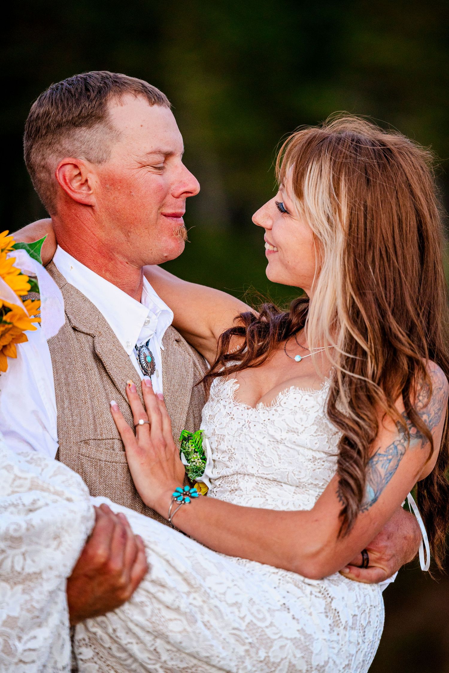 A couple shares an intimate moment in wedding attire with sunflower decorations.