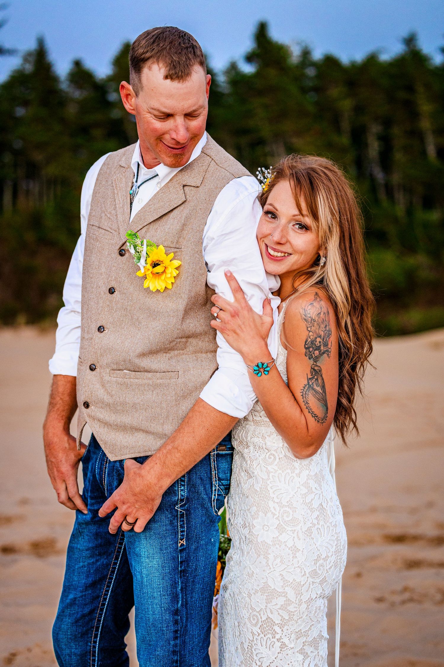 A casual beach wedding photo featuring a couple in rustic attire with sunflower accents.