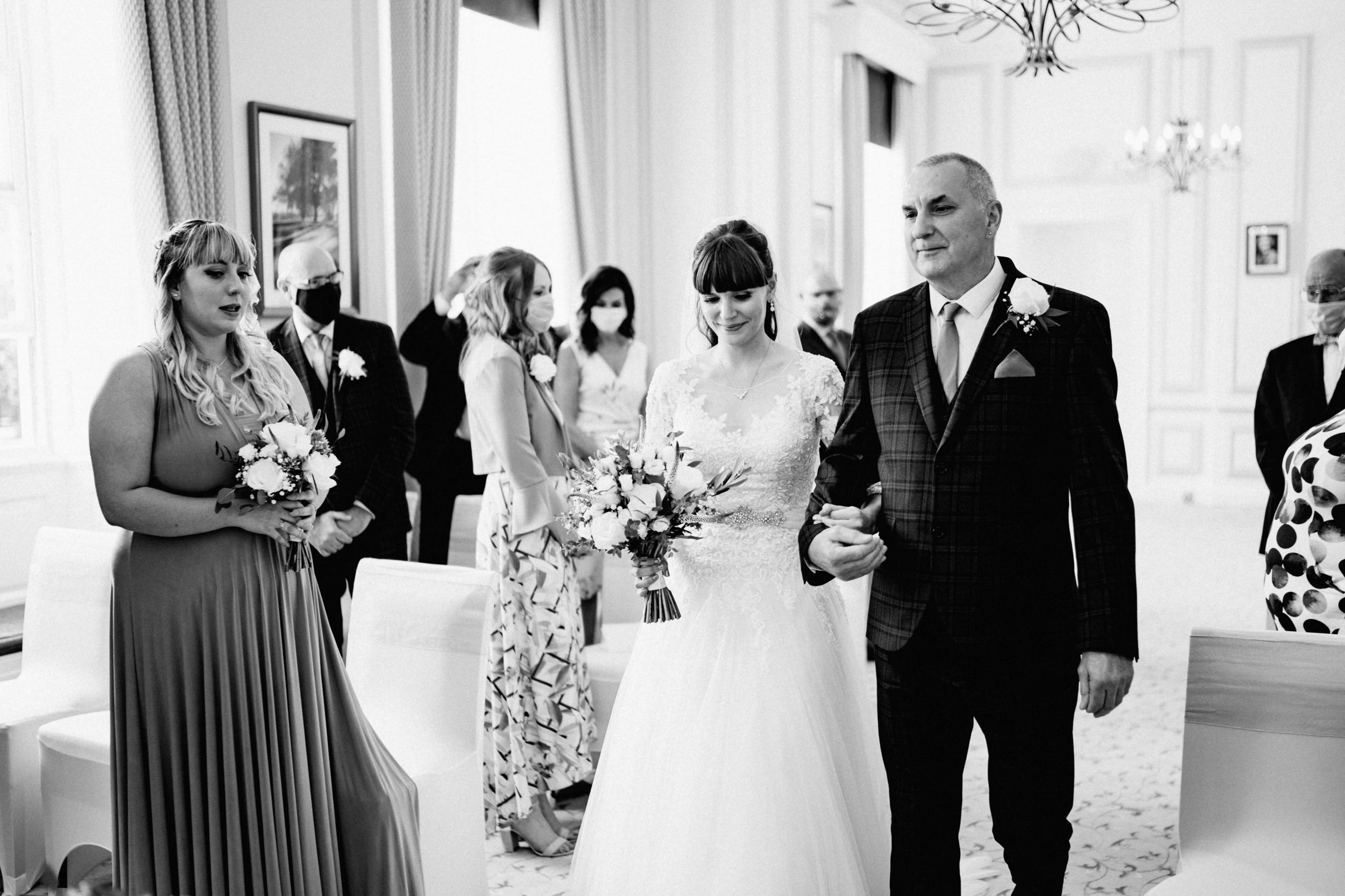 Black and white photo of wedding ceremony with attendees in formal attire.