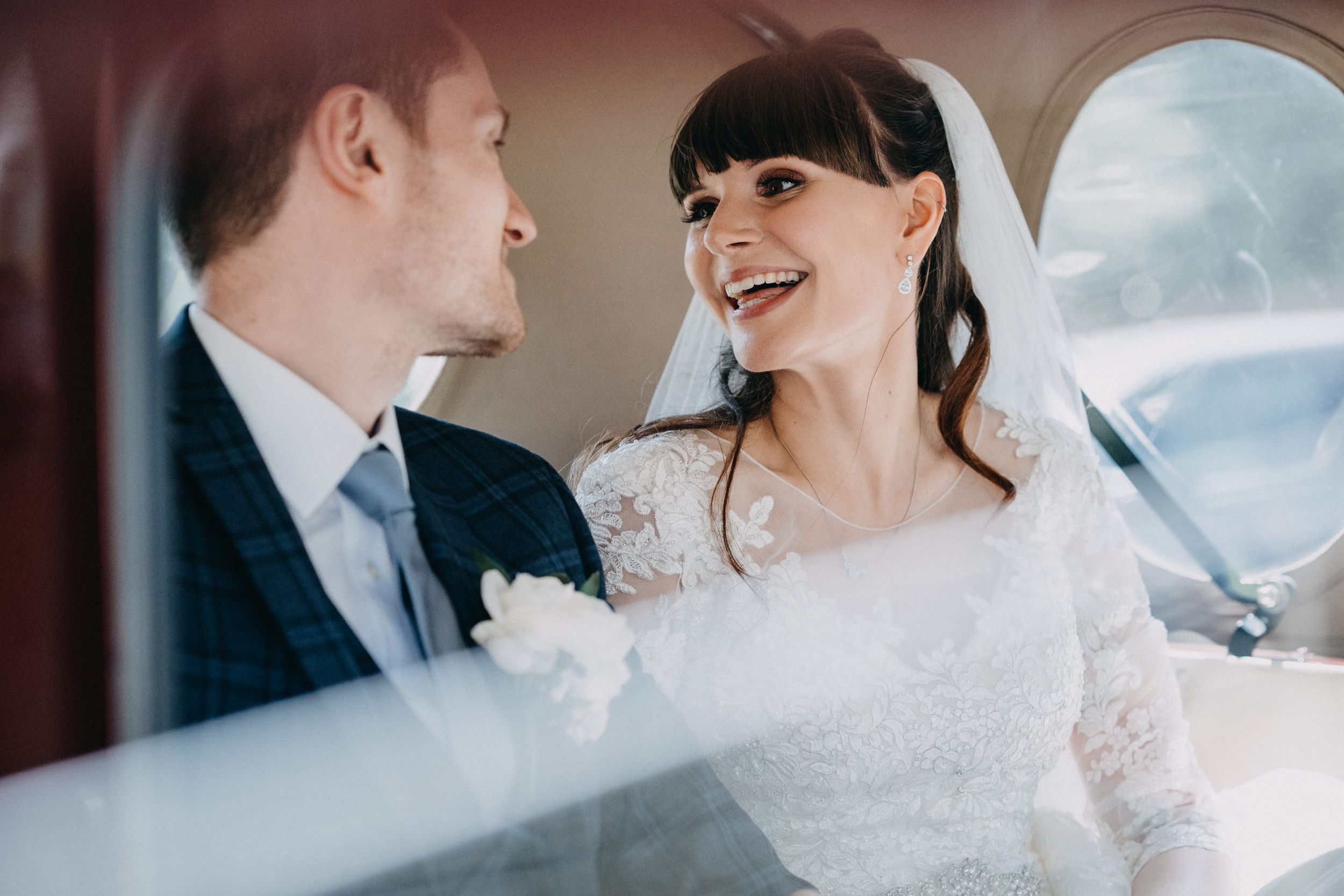 Joyful moment captured inside wedding car with beautiful lace dress detail.