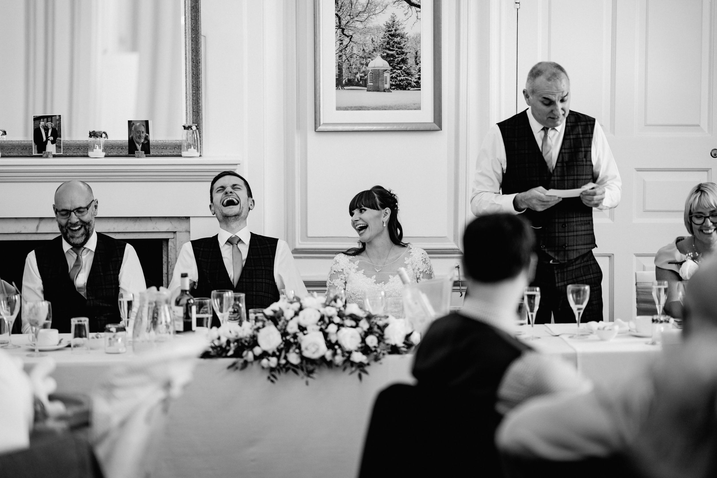 A black and white photograph of wedding speeches during a formal reception dinner.