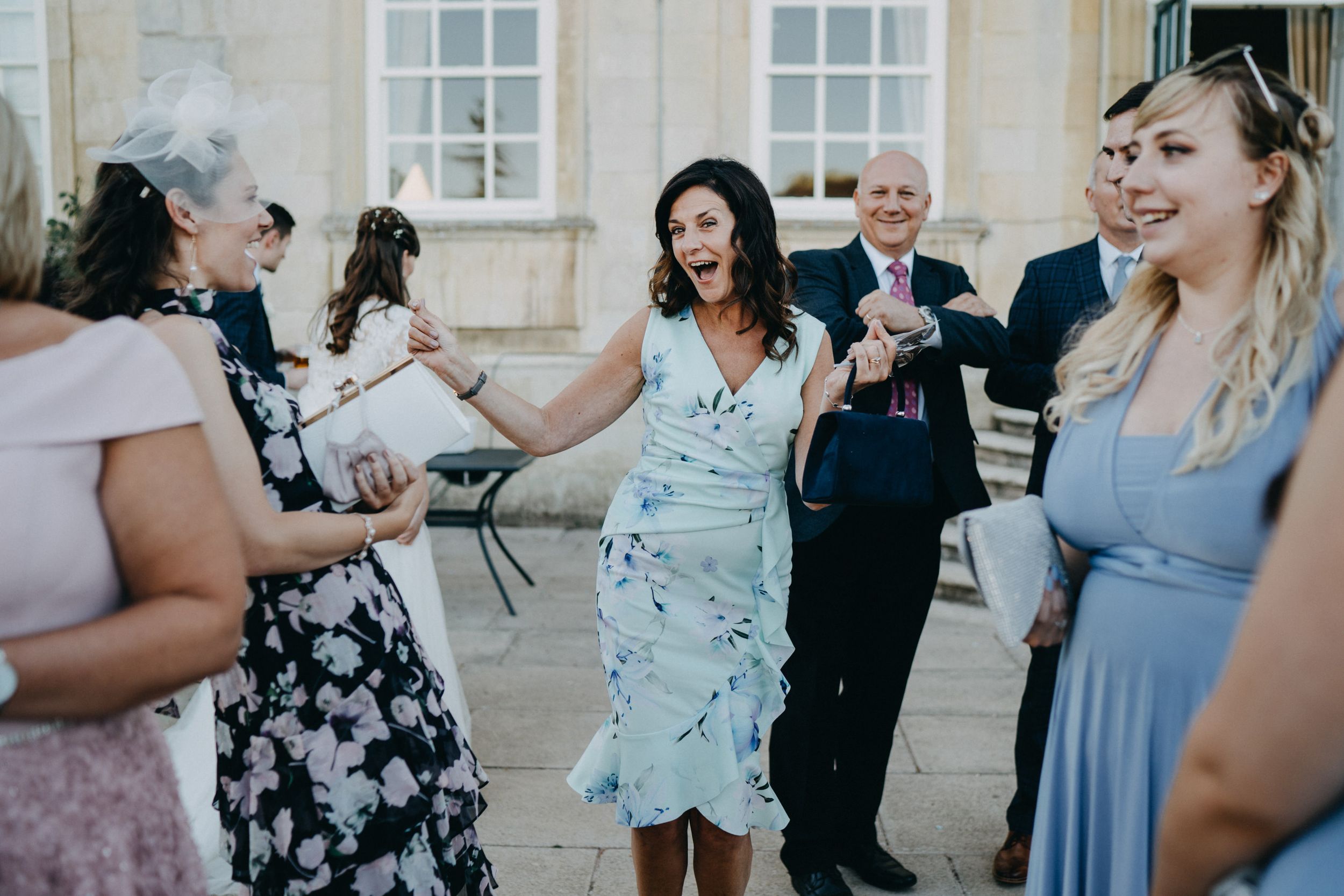 Wedding guests mingling and socializing on an elegant stone terrace during a reception.