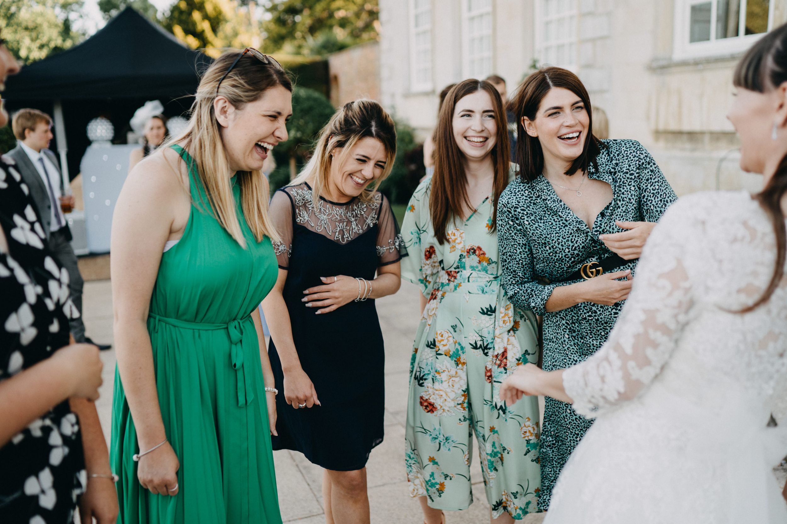 Wedding guests in colorful dresses enjoying conversation during outdoor celebration.