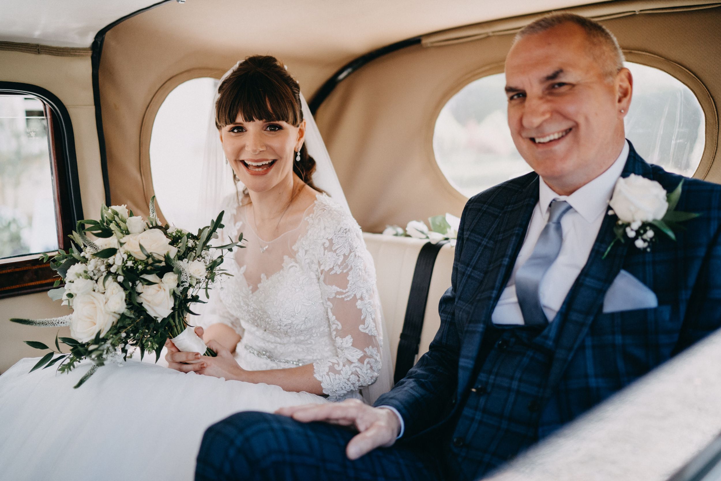 Newlyweds share a joyful moment inside vintage wedding car.