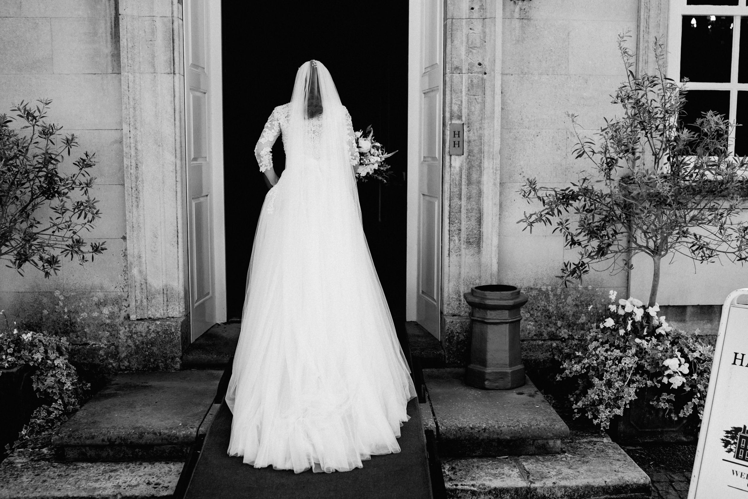 Silhouette of bride in flowing wedding dress standing in doorway of historic building.