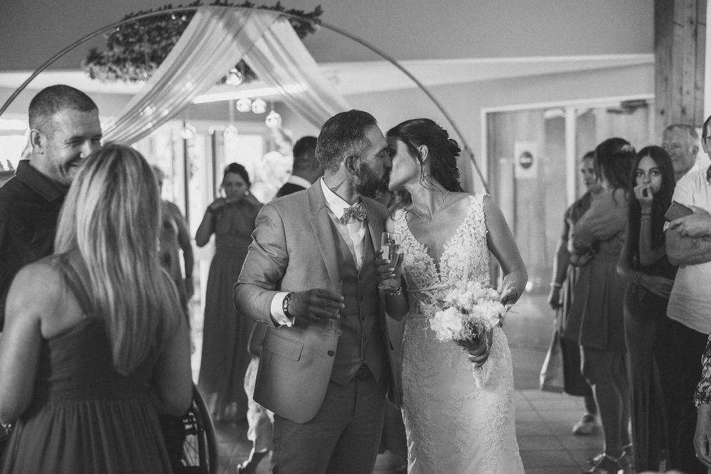 A joyful celebration at an indoor wedding reception with guests dancing.